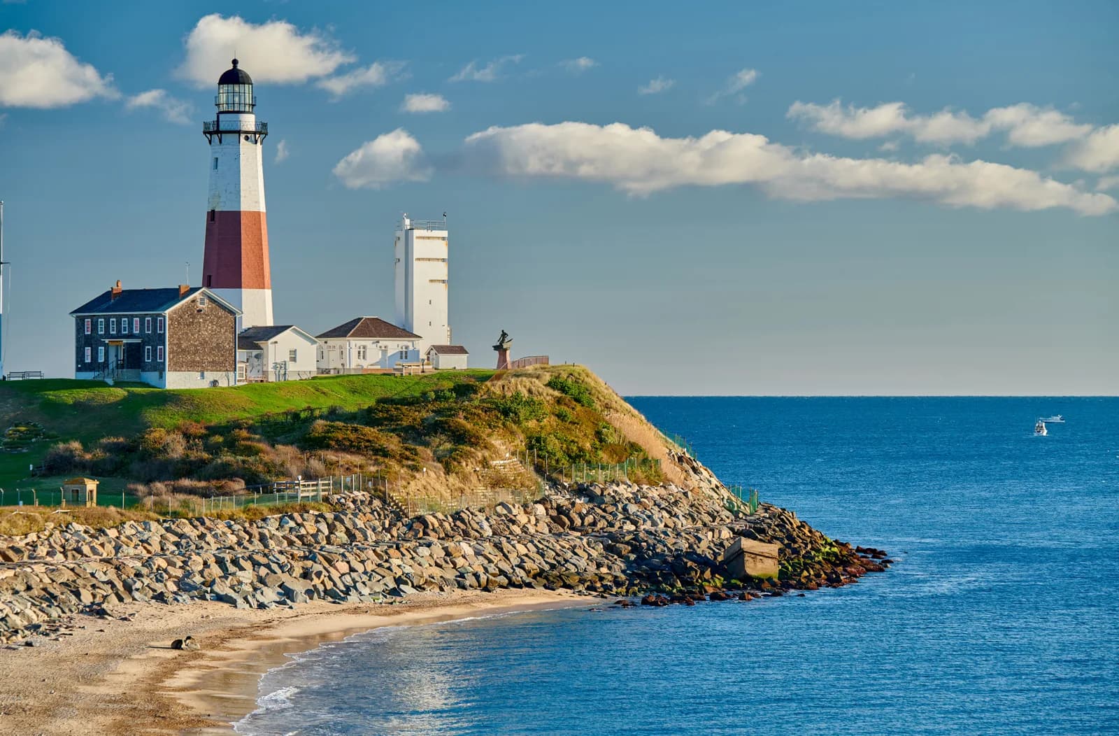 The Montauk Point lighthouse on a grassy bluff above a rocky shore and open ocean