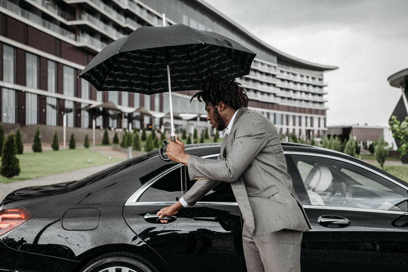 Chauffeur in a suit opening the door of a black sedan