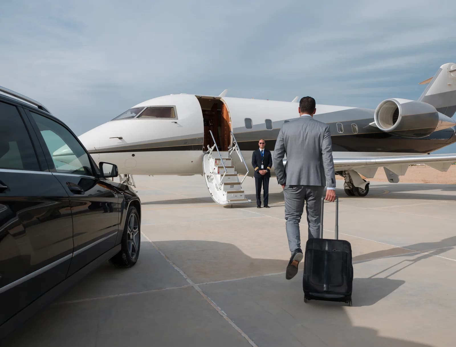 A principal walking from a black car to a waiting private jet