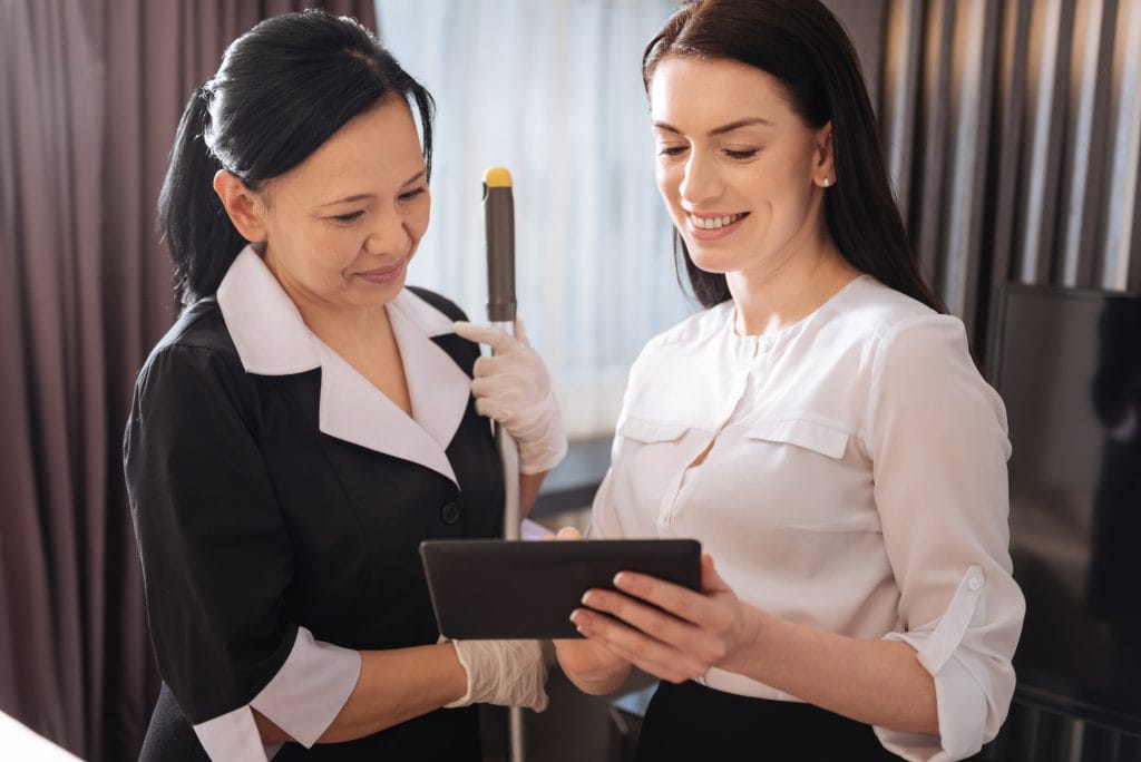 Joyful pleasant women looking at the tablet screen Live-in Housekeeper